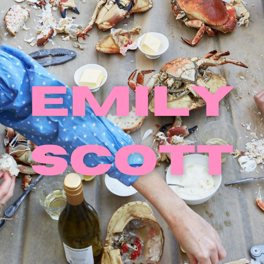 Blog post about independent female owned businesses in the UK written for Tide and Seek Sustainable swimwear - image of lots of cooked crabs on a wooden table surrounded by lots of dips, butters, oils and garlic as well as chilies with a arm reaching across dipping a piece of crab. Over the top of the image is pink text 'Emily Scott'. 