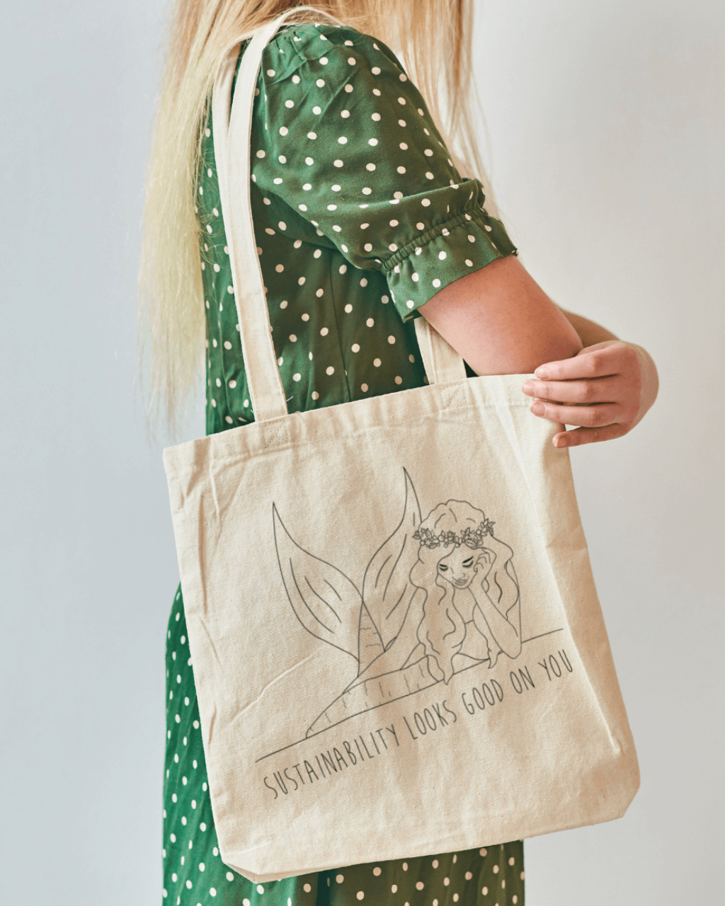Tide and Seek Sustainable Swimwear Tote bag in studio setting on faceless model in a green dress wearing the bag on her shoulder.