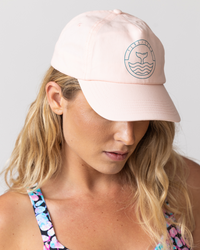 tide and seek sustainable swimwear model wearing pink logo cap